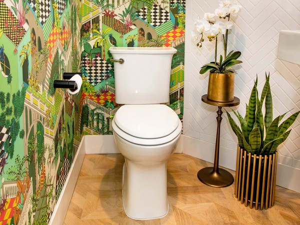 Jungle themed bathroom with green wallpaper, white toilet and several green plants