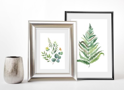 Small silver jar next to two framed photos of ferns