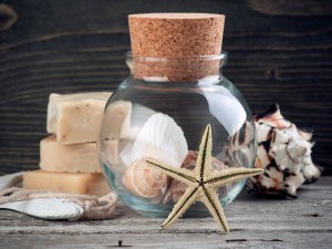 Stack of handmade soap next to round glass jar with shells and starfish