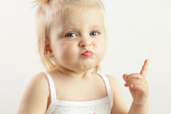 Feisty toddler girl with pursed lips and index finger raised