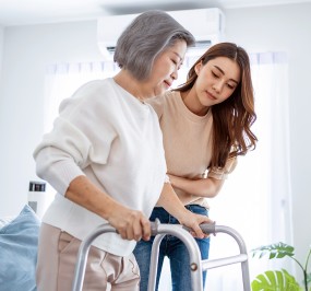 Younger woman helping elderly woman using a walker