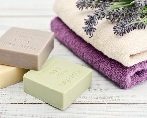 Three blocks of soap next to folded purple and tan towels