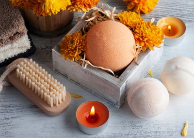 Arrangement showing hand brush, orange candle and box of orange flowers with bath bomb