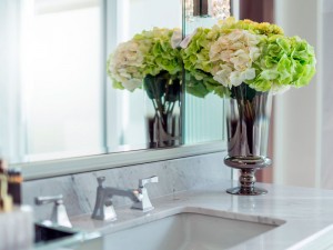 Vase of green and white flowers on grey bathroom sink