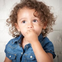 Small child with curly brown hair and a hesitant expression