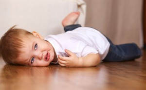 Toddler boy lying on the floor, looks sad or frustrated