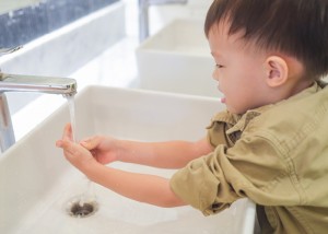 Small boy washing his hands at the bathroom sink