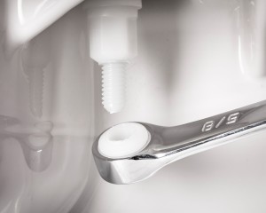 Side of toilet bowl showing a wrench installing Bemis toilet seat hardware
